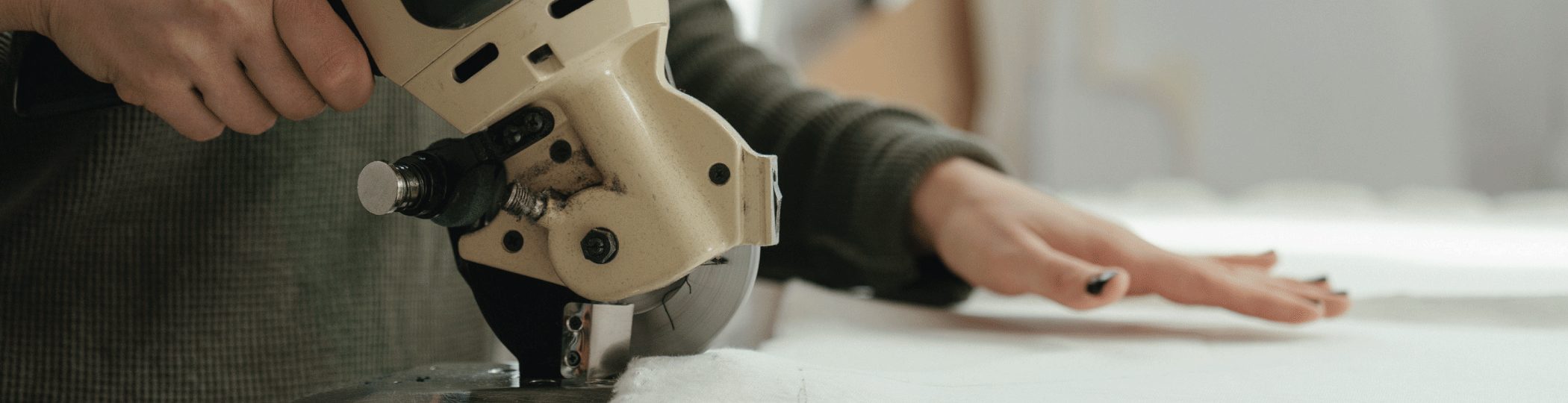 A fabric cutter slicing through a stack of white fabric